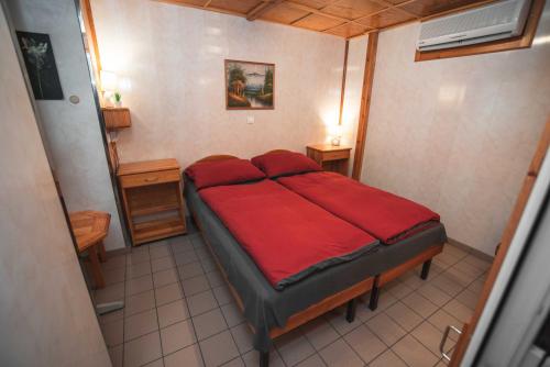 Bett in einem kleinen Zimmer mit einer roten Decke in der Unterkunft Duna-Party Pansion in Budapest