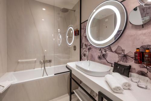 a bathroom with a sink and a tub and a mirror at H10 Palazzo Galla in Rome