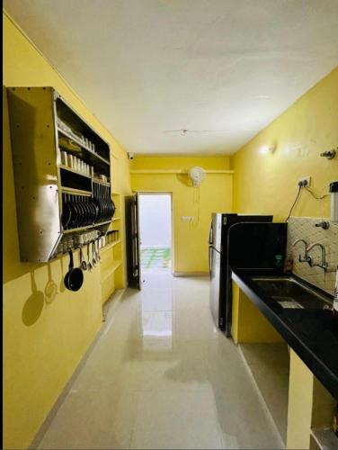 a kitchen with yellow walls and a sink and a refrigerator at Hostel ivory in Jaipur
