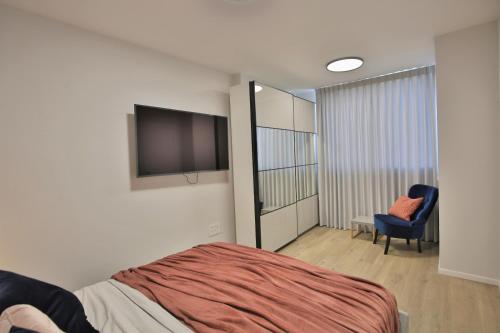 a bedroom with a bed and a tv and a chair at Cozy and stylish 1-bedroom apartment in Netanya