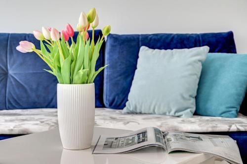 a vase of flowers on a table with a newspaper at Apartamenty Piamola Jantar Park in Jantar