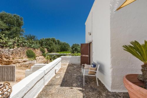 a chair sits on the side of a white building at Masseria La Cazzigna by Perle di Puglia in Pezze di Greco