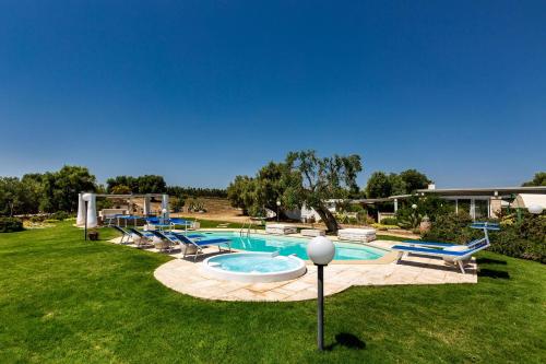 a swimming pool with chairs around it in a yard at Masseria La Cazzigna by Perle di Puglia in Pezze di Greco