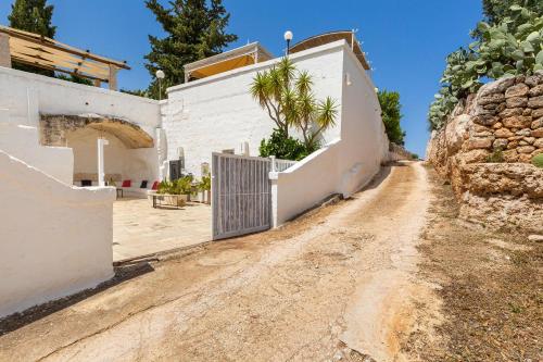 a dirt road next to a white building with a gate at Masseria La Cazzigna by Perle di Puglia in Pezze di Greco