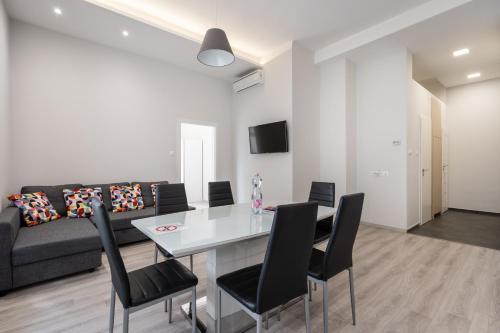 ein Wohnzimmer mit einem Tisch, Stühlen und einem Sofa in der Unterkunft Cascade Corvin Apartment in Budapest