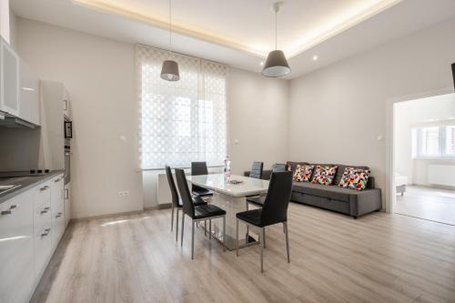 ein Wohnzimmer mit einem Tisch, Stühlen und einem Sofa in der Unterkunft Cascade Corvin Apartment in Budapest