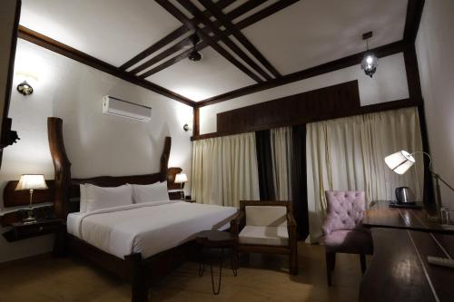 a bedroom with a bed and a desk and a chair at Jagira Ananta Elite , Sasan Gir in Chitrod
