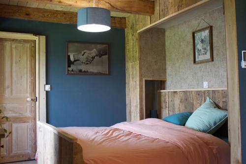 a bedroom with a bed and a blue wall at Chez de Vergne in Chanterelle