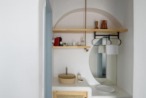 a small bathroom with a sink and a shelf at Kalestesia Suites in Akrotiri