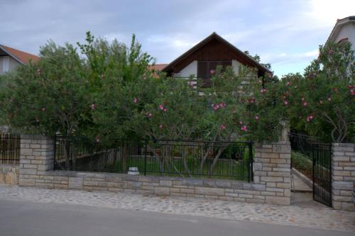 a fence with trees and pink flowers on it at kuća za odmor Anić in Pirovac