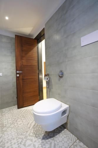 a bathroom with a toilet and a wooden door at Jagira Ananta Elite , Sasan Gir in Chitrod