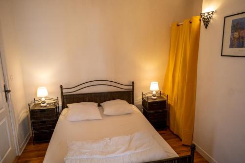 a bedroom with a bed with two nightstands and two lamps at Appartement place Des Cordeliers in Dinan