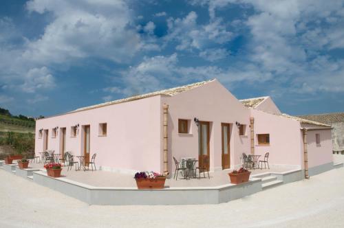 Casa blanca con mesas y sillas en un patio en Baglio Antico, en Fulgatore