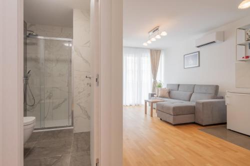 a bathroom with a shower and a living room with a couch at Luxury Apartment Solinka With Private Parking in Solin