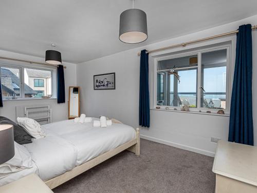 a bedroom with a bed and two windows at Pass the Keys Sea View Apartment in centre of Rhosneigr in Rhosneigr