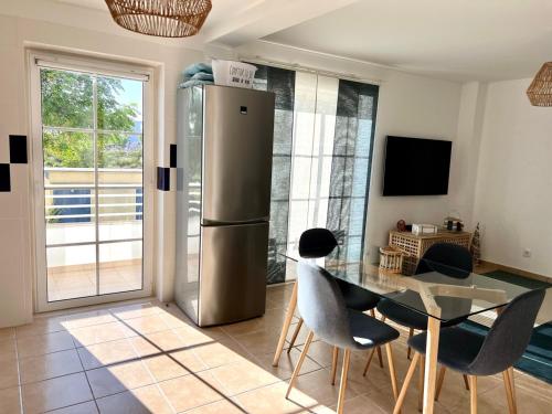 a kitchen with a stainless steel refrigerator and a table at Cabanas Wonder - 150mts from the beach in Cabanas de Tavira
