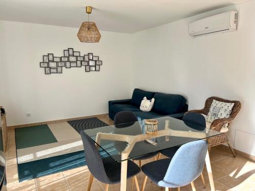 uma sala de estar com uma mesa de vidro e cadeiras em Cabanas Wonder - 150mts from the beach em Cabanas de Tavira