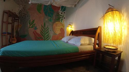 a bedroom with a bed with a painting on the wall at Corto Novo Maison d'hôtes-Camping in Nosy Be