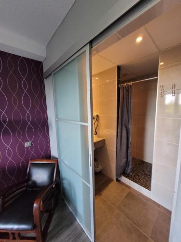 a chair in a room with a shower and a toilet at Hôtel Restaurant Les Alizés in Lipsheim