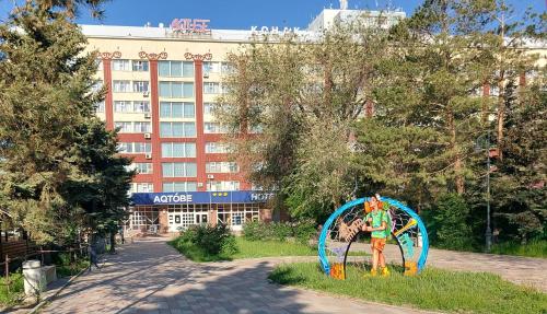 Une statue dans l'herbe devant un bâtiment dans l'établissement Aktobe Hotel, à Aqtöbe