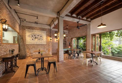 a restaurant with tables and chairs and a brick wall at Korurua Dijiwa Ubud in Ubud