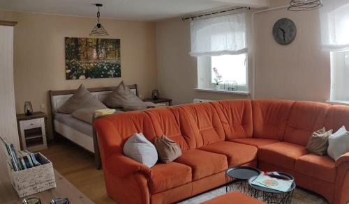 ein Wohnzimmer mit einer orangefarbenen Couch mit Kissen in der Unterkunft Ferienwohnung Zum Ausblick in Kurort Altenberg
