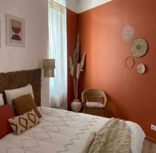 a bedroom with orange walls and a bed and a chair at T2 L'Evasion - TERRASSE - PARKING gratuit - Climatisation in Bagnères-de-Bigorre