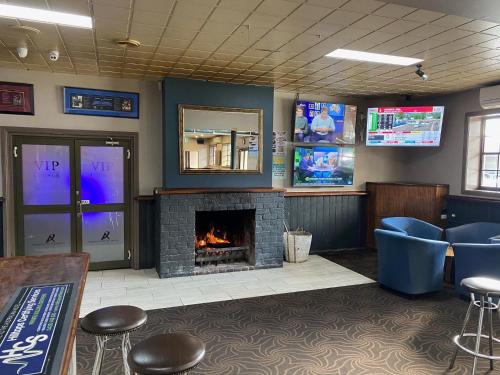 a waiting room with a fireplace and blue chairs at Australian Hotel Young in Young