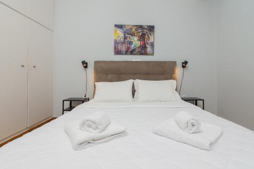 a white bed with two white towels on it at Kerameikos Metro Apartment for 4 in Athens