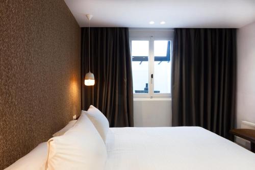 a bedroom with a white bed and a window at SV Acropolis Residence in Athens