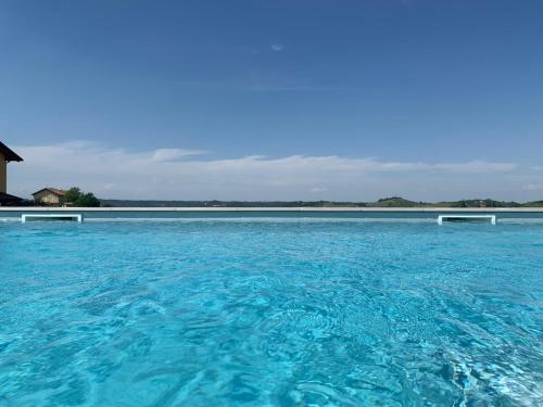 a large pool of blue water in front of a house at Al Tirabusòn Country House in Nizza Monferrato