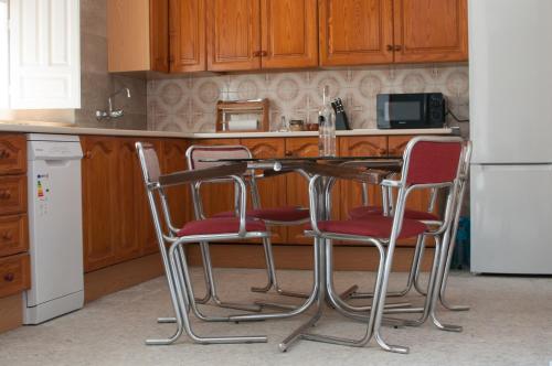 eine Küche mit 3 Stühlen, einem Tisch und einem Kühlschrank in der Unterkunft CASA BEATLES DEL VALLE in Pinos del Valle