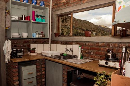 a kitchen with a counter with a sink and a window at Kalkfontein Guesthouse in Merweville