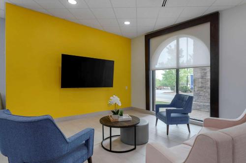 a waiting room with chairs and a tv on a yellow wall at Comfort Suites Mt Juliet-Nashville Area in Mount Juliet