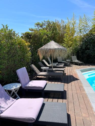 a group of lounge chairs and an umbrella next to a swimming pool at Le Synaya in Sanary-sur-Mer