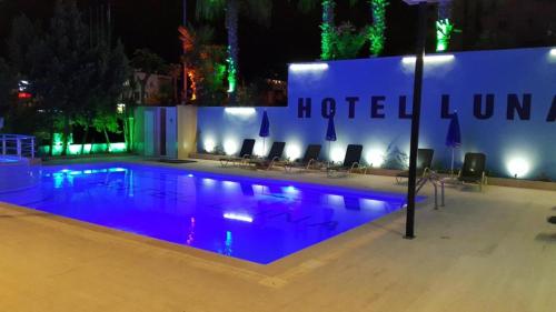 a swimming pool at night with chairs and a building at Luna Lara Hotel in Antalya