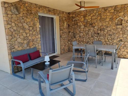 un patio avec des chaises et des tables ainsi qu'un mur en pierre dans l'établissement A Dugana, à Lecci