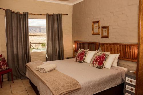 a bedroom with a large bed with a window at Kalkfontein Guesthouse in Merweville