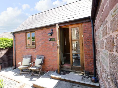 a small brick house with two chairs and a door at The Cider Loft in Ross on Wye