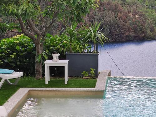 a white table and chair next to a swimming pool at Eira House - Quinta de Fundevila in Vieira do Minho