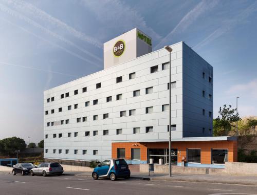 a white building with a car parked in a parking lot at B&B HOTEL Barcelona Granollers in Les Franqueses del Vallès