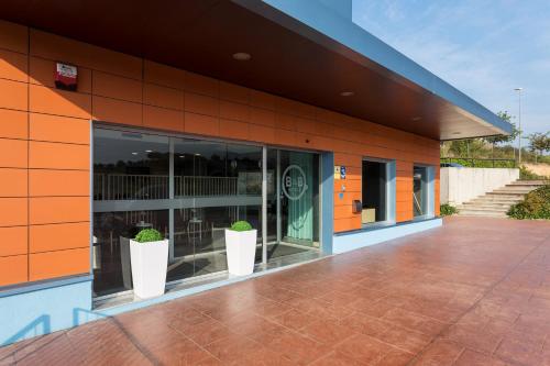 a building with two potted plants outside of it at B&B HOTEL Barcelona Granollers in Les Franqueses del Vallès
