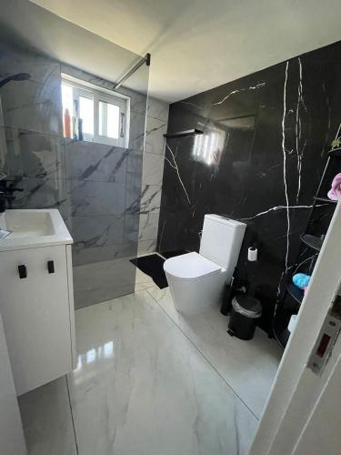 a bathroom with a white toilet and a black wall at Oneiro Napa Suite in Ayia Napa