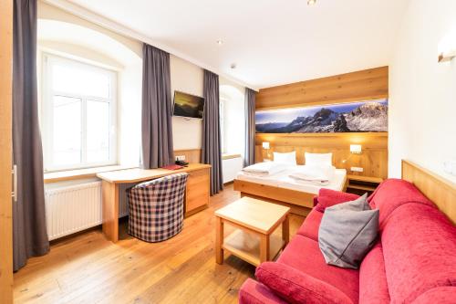 ein Wohnzimmer mit einem roten Sofa und ein Schlafzimmer in der Unterkunft Hotel Heitzmann in Mittersill