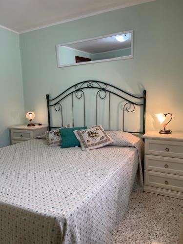 a bedroom with a bed with a white bedspread and two night stands at Attico a San Vito Lo Capo in San Vito lo Capo