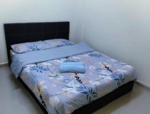 a bed with a blue comforter and two pillows at Cocobay Resort Cosy Apartment in Kampong Tanah Merah