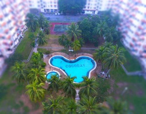 an aerial view of a pool with palm trees at Cocobay Resort Cosy Apartment in Kampong Tanah Merah