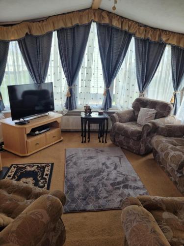 a living room with couches and a flat screen tv at Discover comfort home from home 8-birth Caravan in Skegness