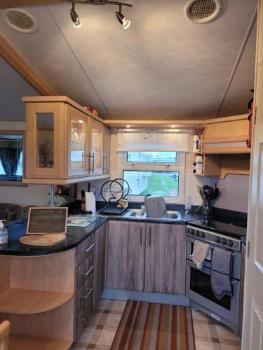 an rv kitchen with wooden cabinets and a counter top at Discover comfort home from home 8-birth Caravan in Skegness