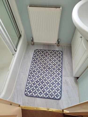 a bathroom with a sink and a blue and white rug at Discover comfort home from home 8-birth Caravan in Skegness